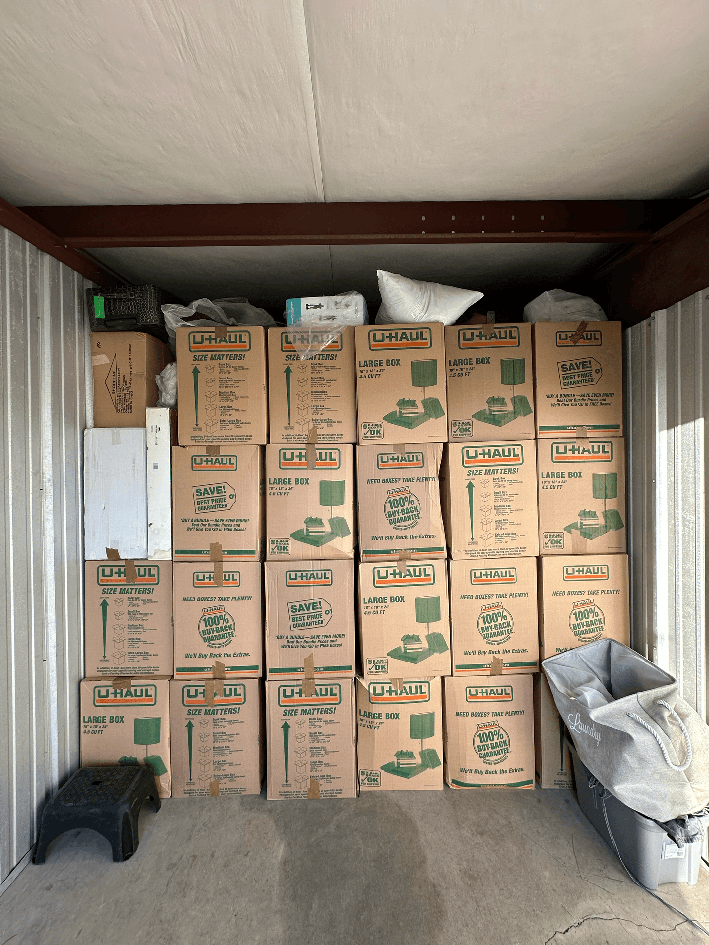 Storage unit filled with stacked U-Haul boxes and various household items.